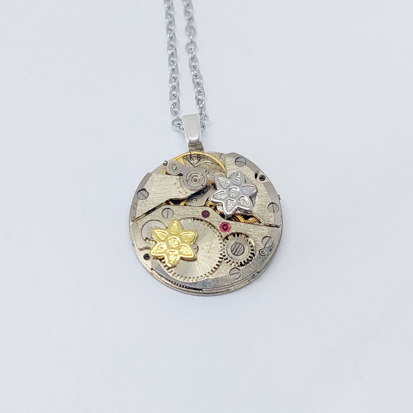 Small timepiece pendant with mixed metal flowers